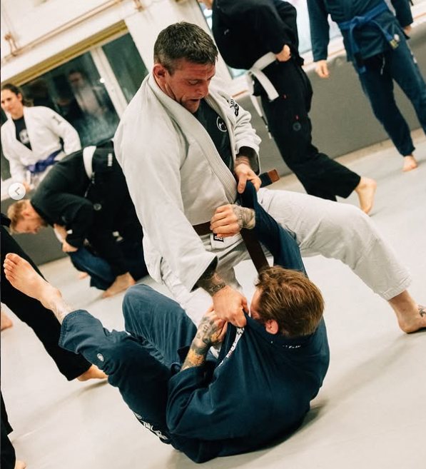 Brown belt working to pass the guard of a partner in a blue gi