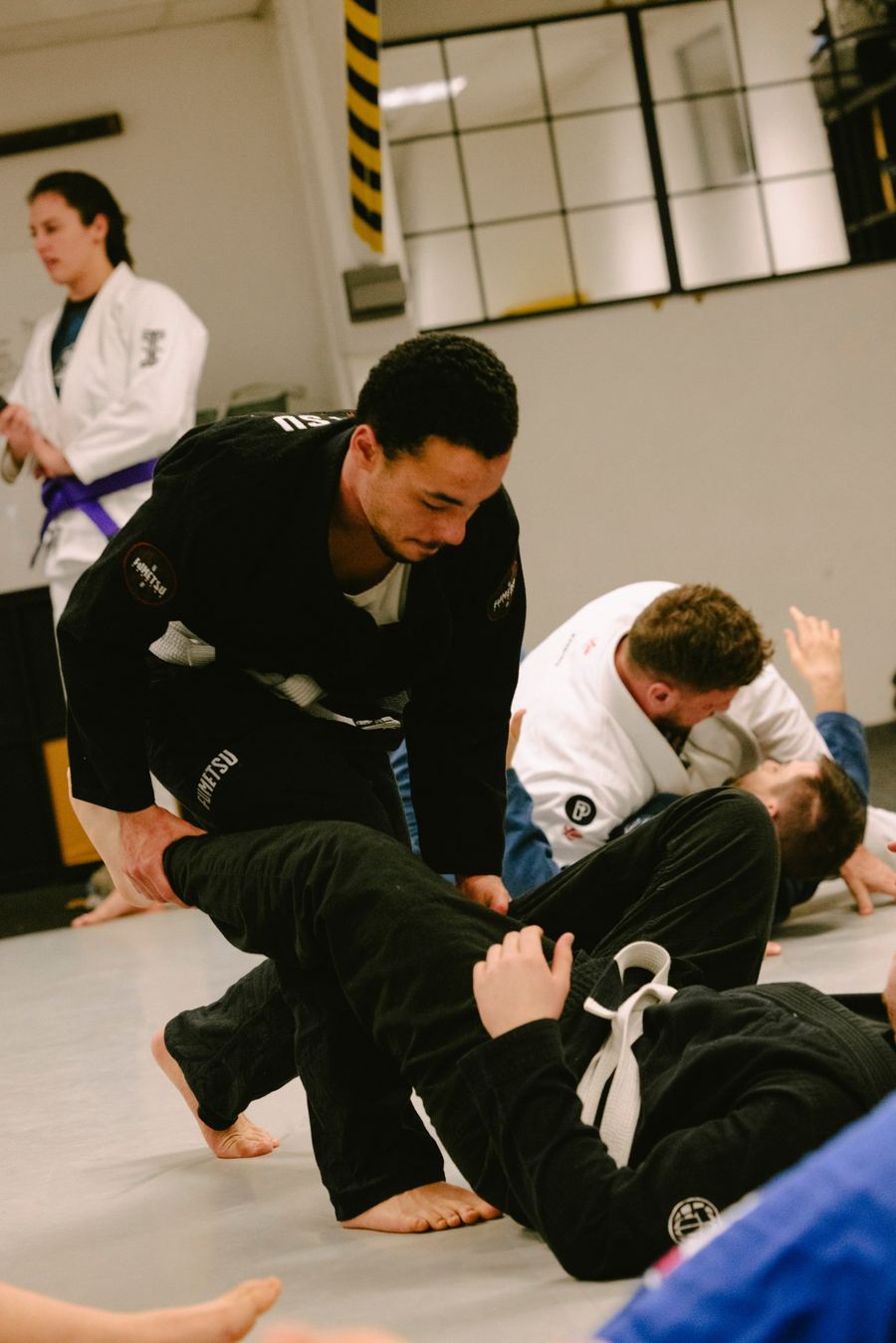 Black gi student passing a partner's guard during a Gi class